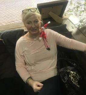 Woman with elf on shoulder sitting on couch.
