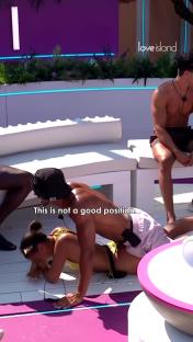 Screenshot from Love Island showing a couple in an awkward position during a game.