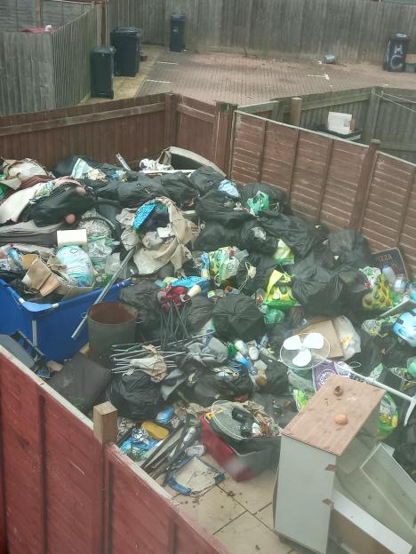 A large pile of garbage in a backyard.