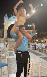 Woman sitting on a waiter's shoulders at a restaurant.