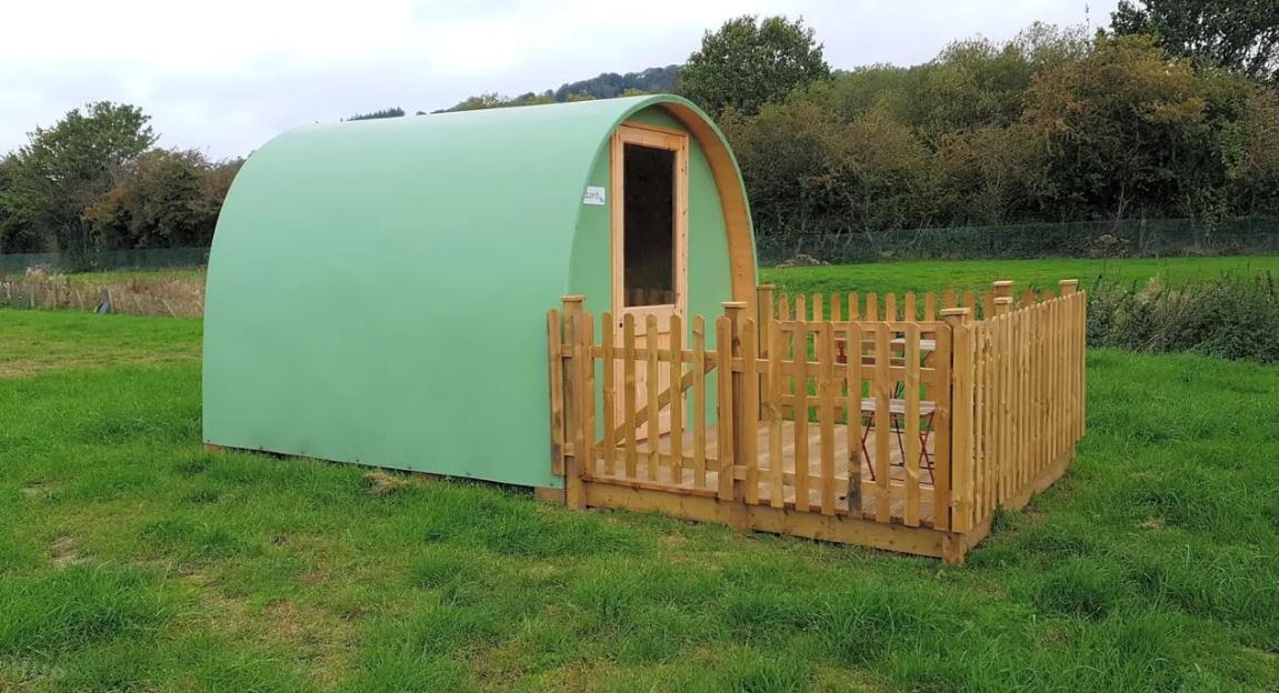Green camping pod with wooden fence and deck.