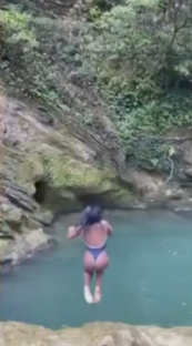 Person cliff jumping into a pool of water.