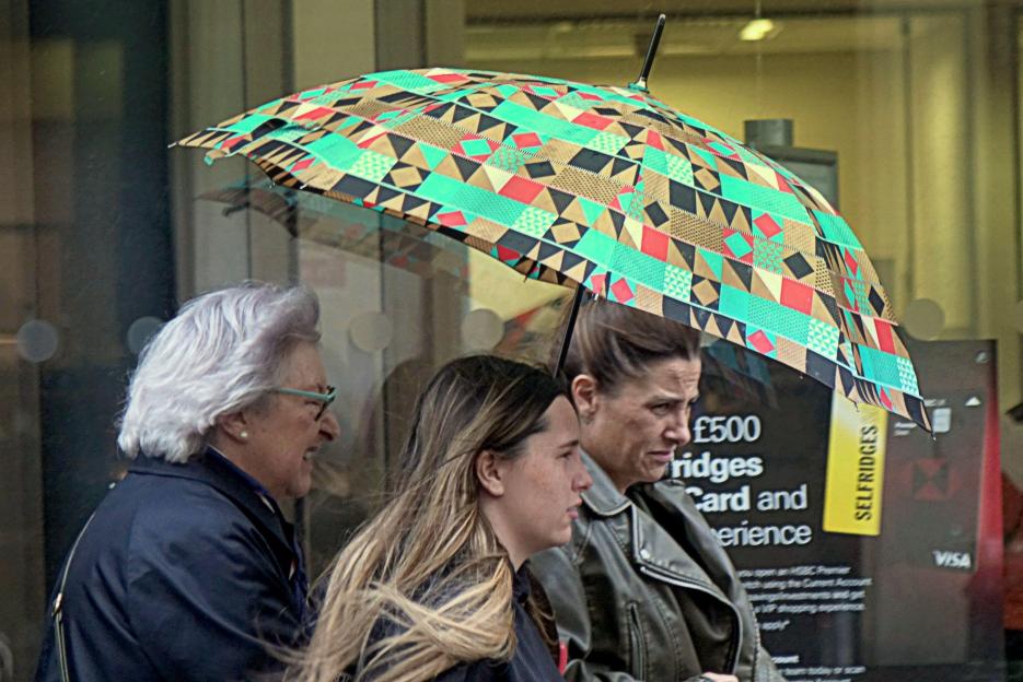 Shoppers sharing an umbrella in the rain.