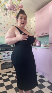 Woman in black dress in a kitchen.