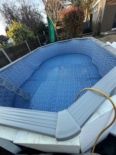 A partially filled backyard swimming pool with a blue and white patterned liner.