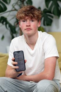 Teenage boy holding a smartphone.
