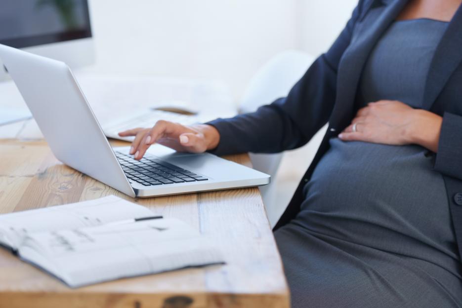 Pregnant businesswoman working on a laptop.