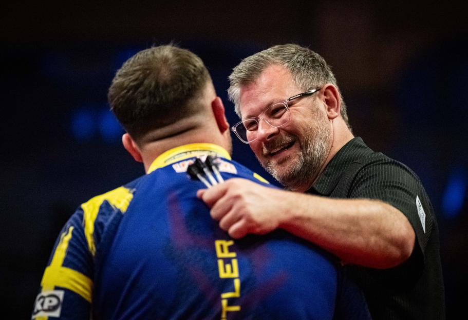 James Wade congratulates Luke Littler after a darts match.