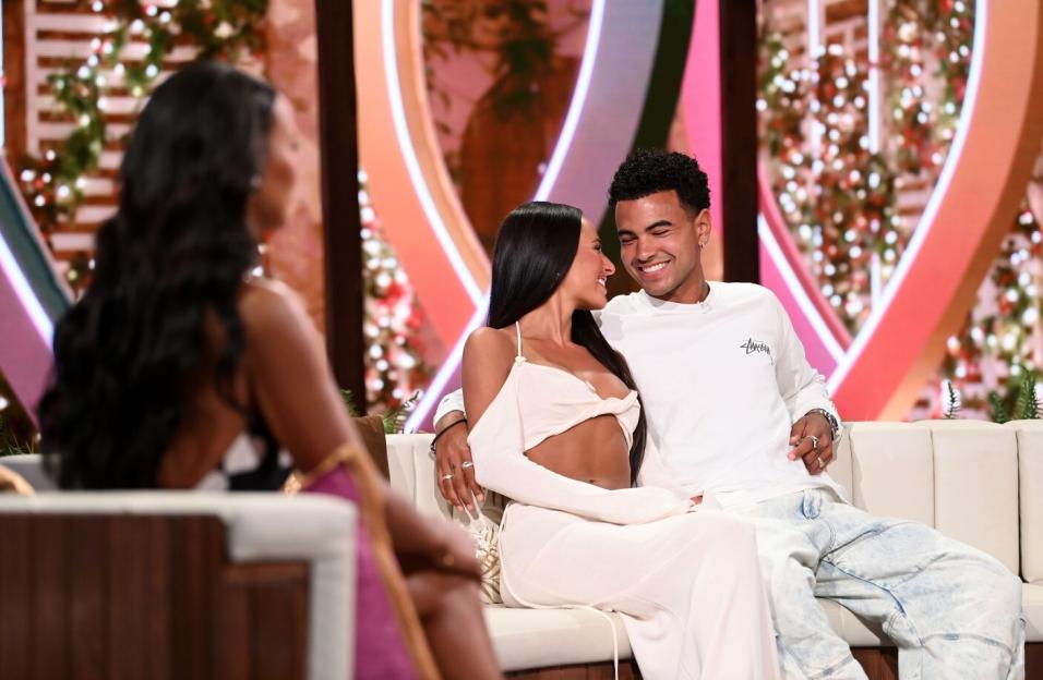 Couple sitting on a couch, smiling at each other.