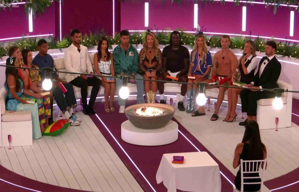 Group of Love Island contestants sitting around a fire pit.