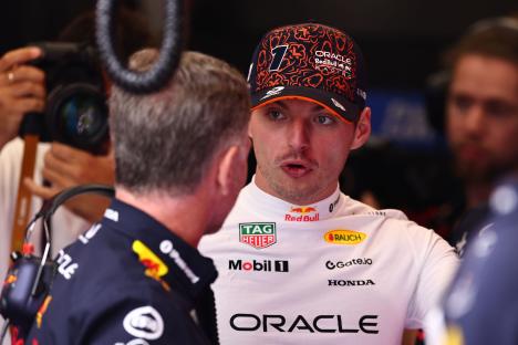 Max Verstappen and Christian Horner speaking at a Formula One practice session.