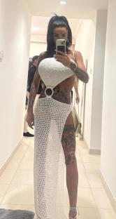Woman in white crochet dress taking selfie.