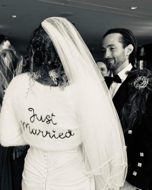 Black and white photo of a bride and groom on their wedding day. The bride's sweater says