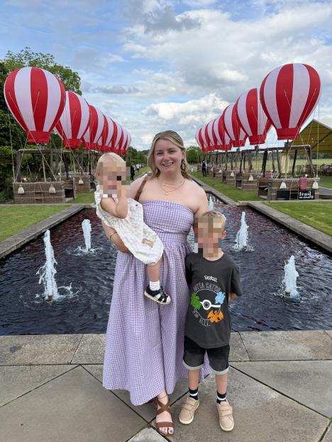 Woman with two young children in front of hot air balloon displays.