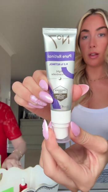 Woman holding up a tube of No7 Pure Retinol 0.3% Night Concentrate.