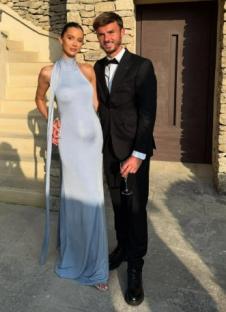 Couple in formal wear posing outdoors.