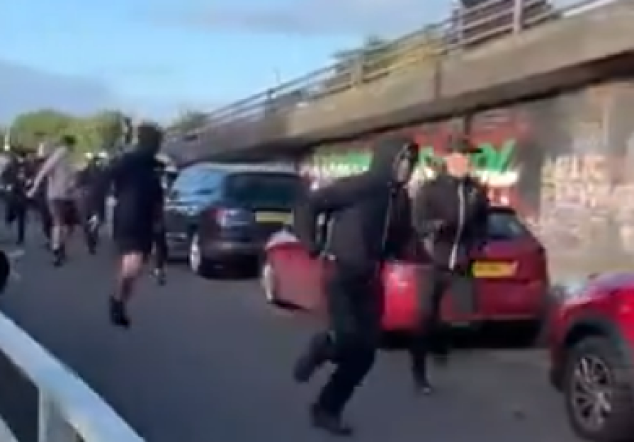 People running in a street near parked cars.