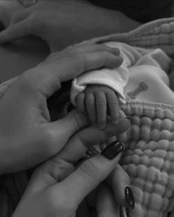 Black and white photo of adult hands holding a newborn's hand.