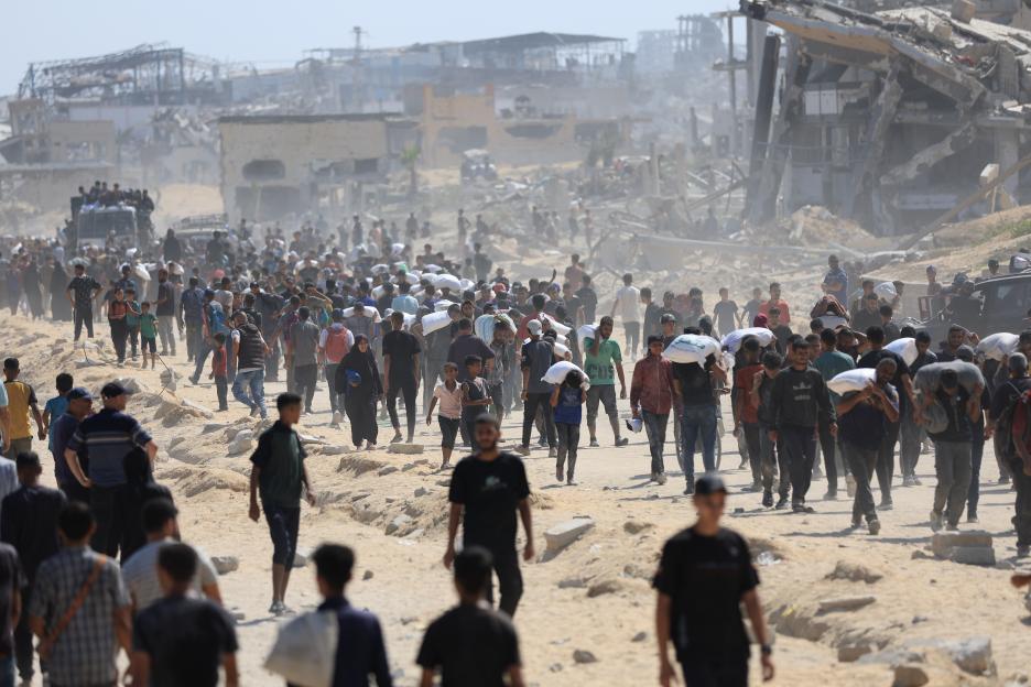Palestinians carrying aid through war-torn streets.