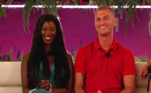 A man and woman smiling on a couch.