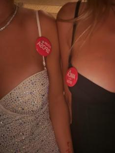 Two women wearing sparkly dresses and hen do buttons.