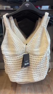 Cream-colored crochet tops on hangers.