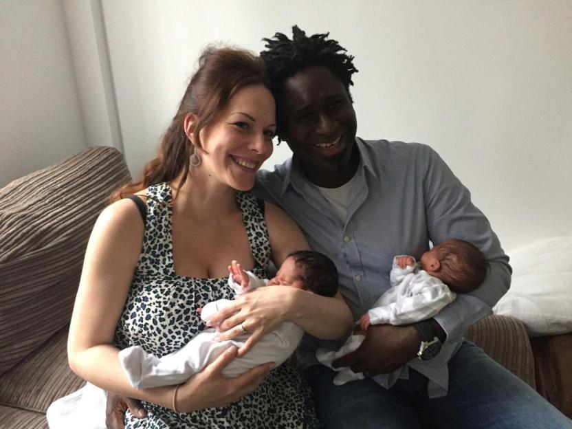 A woman and a man holding their twin babies.