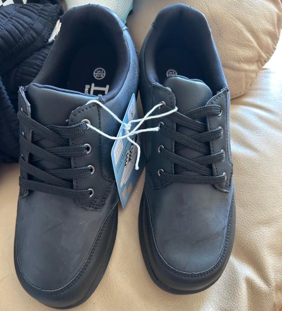 Pair of black children's school shoes with price tag.