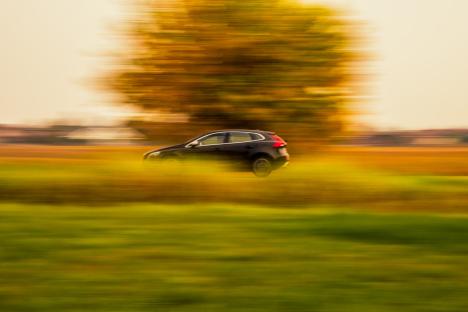 Blurred photo of a car driving past a tree.