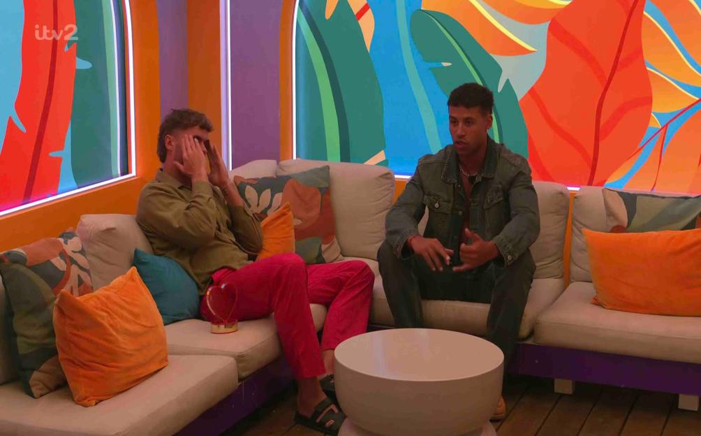Two men sitting on a couch having a discussion.