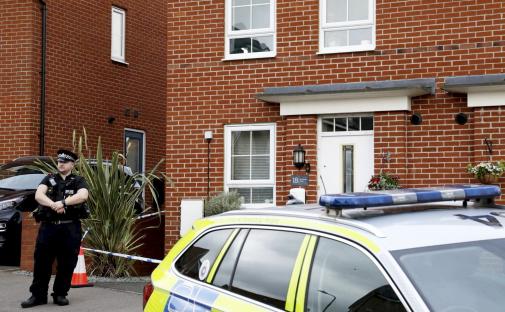 Police officer outside a house where a murder occurred.