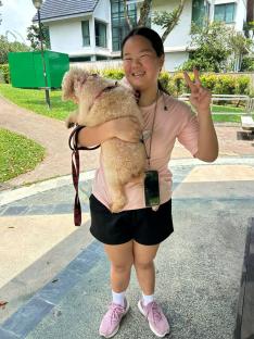 Woman holding a small dog and giving a peace sign.