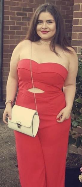 Woman in red jumpsuit and white purse.