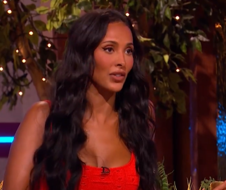 Screenshot of a woman with long dark hair wearing a red top.