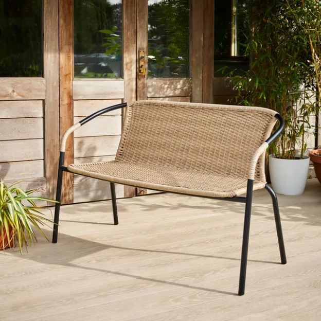 Beige wicker two-seater bench with black metal legs.