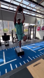 Man performing a fitness exercise with a medicine ball in a gym.