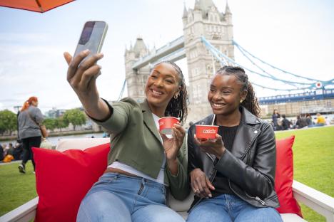Two friends enjoy Nutella ice cream while taking a selfie in front of Tower Bridge.