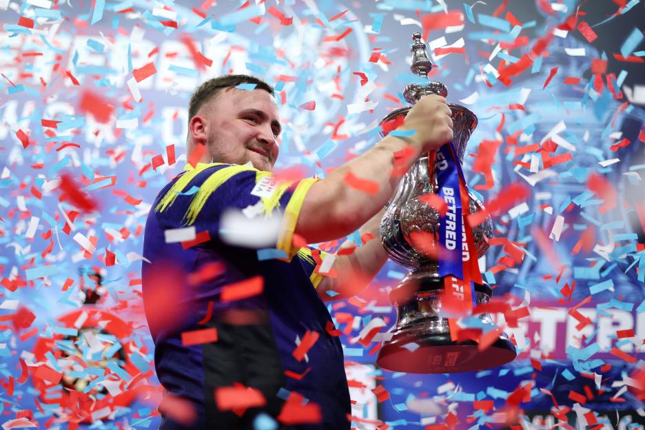 Luke Littler of England celebrates with the Phil Taylor Trophy.