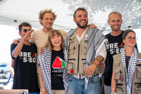 Group of people smiling for a photo, wearing shirts with logos.