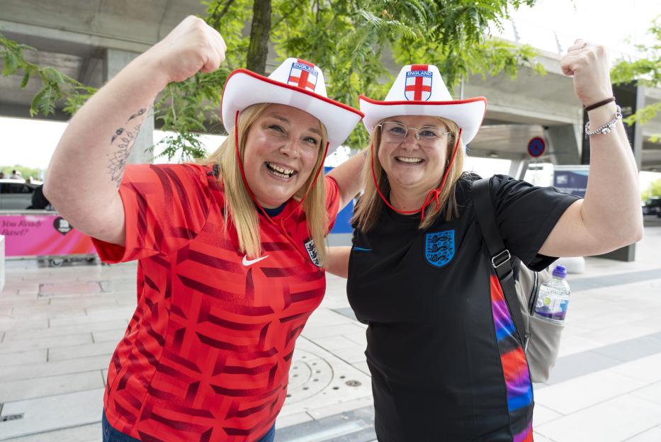 Two England football fans in jerseys and cowboy hats celebrating.