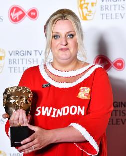 Daisy May Cooper holding a British Academy Television Award.