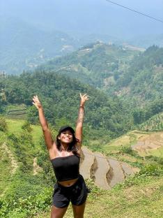 Woman celebrating in front of rice terraces.