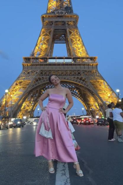 Woman in pink dress in front of Eiffel Tower.