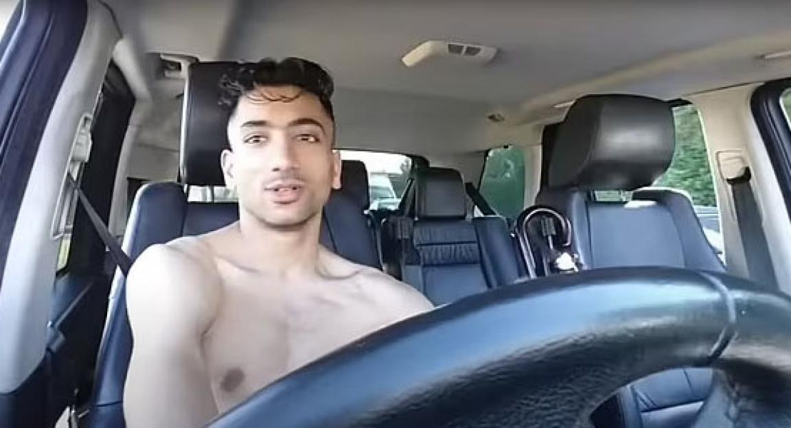 Shirtless man driving a car.