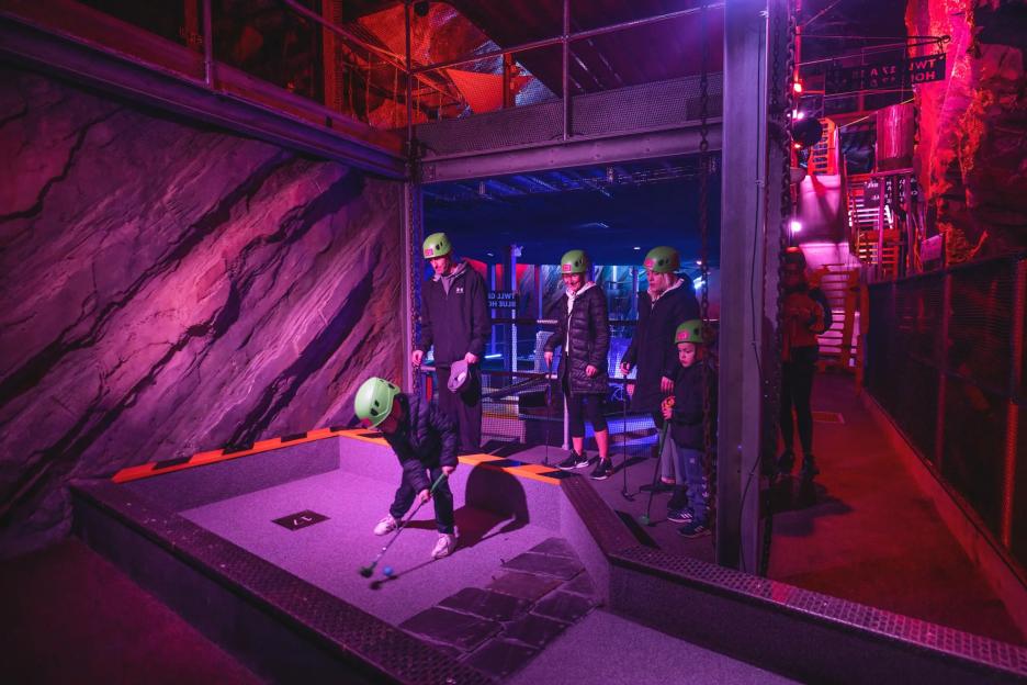 A child plays mini golf in an underground course.