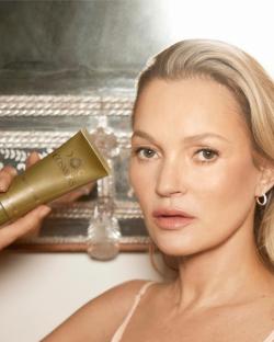 Kate Moss holding Cosmoss face cleanser.