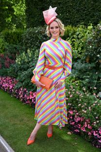Amanda Davies at Royal Ascot wearing a rainbow striped dress and orange hat and shoes.