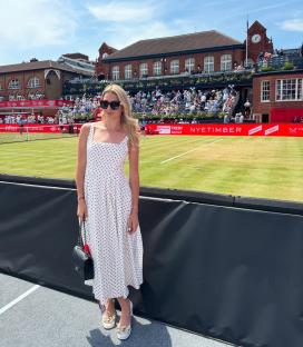 Woman in polka dot dress at a tennis match.