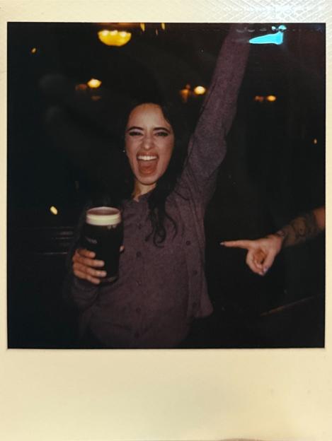 Photo of a woman holding a pint of Guinness and smiling.
