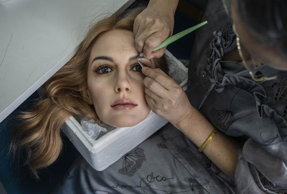 A worker adds hair to a silicone sex doll's head in a factory.